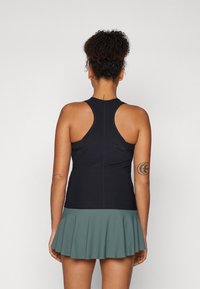 Black sleeveless top with a round neckline and racerback design, paired with a flared teal skort. Smooth fabric with a slightly stretchy texture.