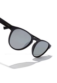 Black sunglasses with a sleek, angular design, dark reflective lenses, and textured black arms featuring a logo inscription.