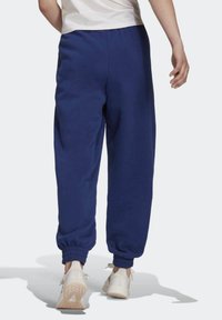 Marineblauwe sweatpants met elastische manchetten en tailleband, gemaakt van een zachte stof. Gekocht met lichtgekleurde sportschoenen.