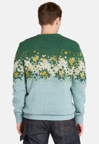 Sweter dzianinowy z zielonym, białym i złotym wzorem geometrycznym w górnej części, przechodzący w jasnoniebieski na dole.