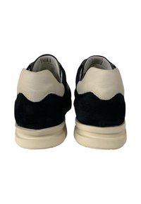 Sneakers in suede blu Navy con un accento in pelle color crema, forma arrotondata, colletto imbottito e sola in gomma beige. Dettagli ondulati sulla pelle.