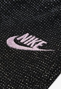 Čierna textúrovaná tkanina s striebornými iskrami, na dolnom pravom rohu je výrazne vyšívané ružové logo Nike.