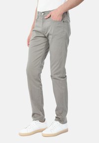 Pantaloni in misto cotone grigio chiaro con vestibilità slim, dotati di tasche frontali e chiusura con bottone, abbinati a sneaker bianche.