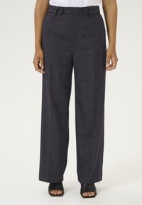 Wide-leg navy trousers with a textured pattern, featuring dual button closures and side pockets. Paired with open-toe black heels.