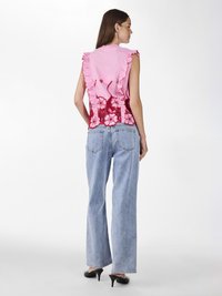 Rosa topp med volanger på skuldrene og rød blonderdetalj bak, kombinert med lyseblå brede ben jeans og svarte hæler.