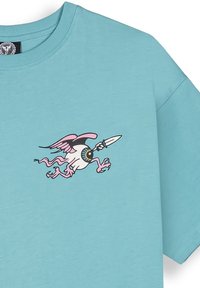 Camiseta turquesa con un gráfico de una criatura de alas pink con una lanza. Tejido suave, corte holgado y diseño de cuello redondo.