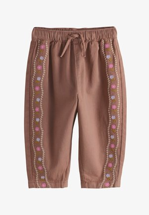 Hnědé kalhoty pro malé děti s elastickým pasem, šňůrkou a vertikálními květinovými vyšívanými pruhy v růžové, fialové a zelené barvě podél nohou.