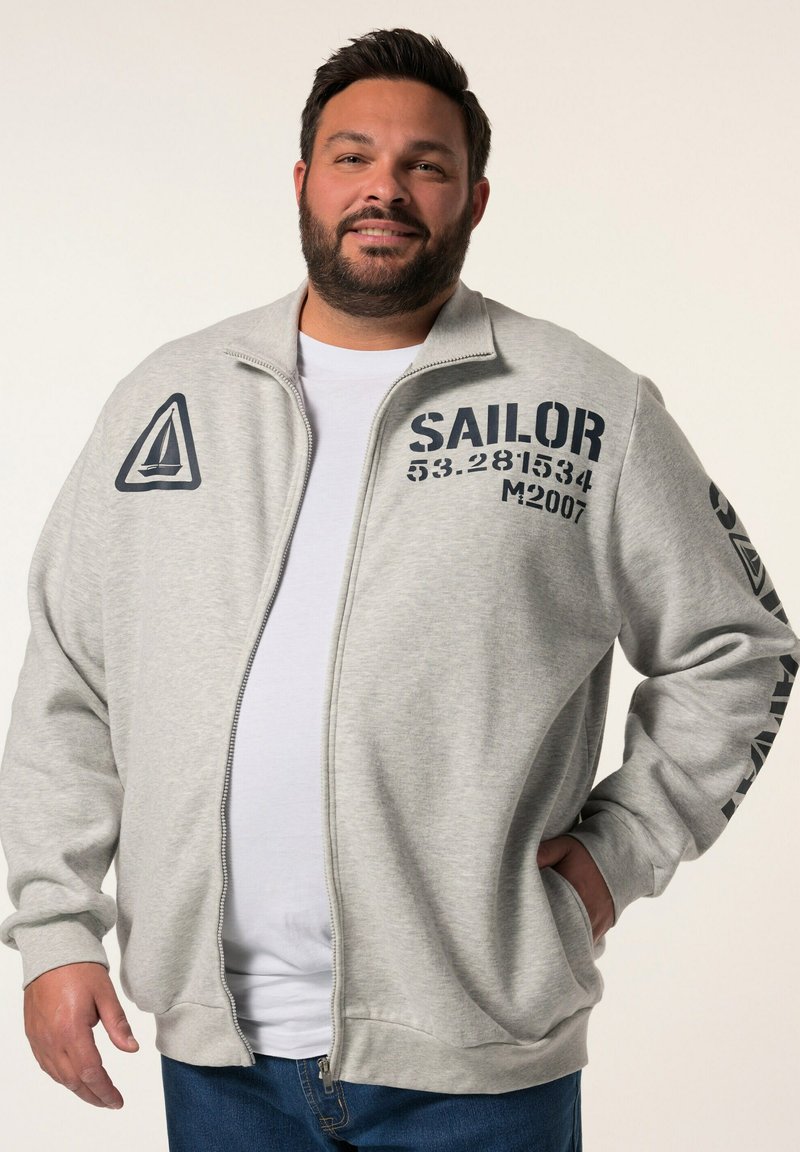 Sudadera gris con cremallera y estampado en azul marino, que presenta un logo de velero, texto "SAILOR" y detalles numéricos en la parte delantera y la manga.