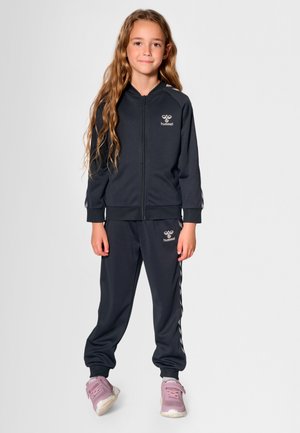 Mørkegråt atletisk træningssæt lavet af et glat stof, med en lynlåsforsynet jakke med logo og matchende bukser med sidelommer.