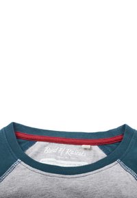 Bomulds T-shirt med en grå krop, teal krave og rød detalje ved halsen. Inkluderer et trykt logo tag indeni kraven.