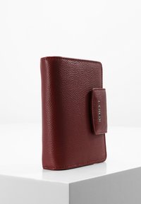 Portefeuille en cuir bordeaux avec une finition texturée, de forme rectangulaire et une fermeture à pression sur le côté. Présente un accent de logo à l'avant.