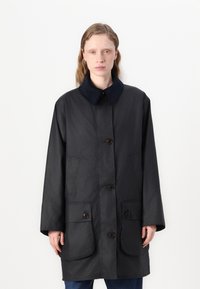 Casaco exterior preto com colarinho de veludo cotelê, fecho frontal por botões e dois grandes bolsos. Textura suave, design de comprimento médio.