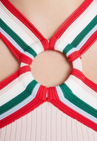 Haut dos nu côtelé avec des bretelles multicolores en rouge, blanc, vert et bleu, reliées par un anneau circulaire central.