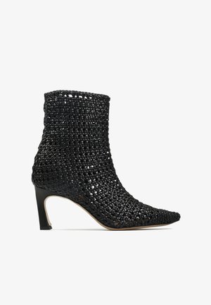 Czarny pleciony botek za kostkę z ostrym noskiem i szerokim obcasem, z teksturowanym, oddychającym wzornictwem i gładką podeszwą.