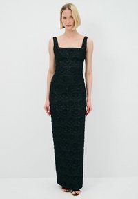 Schwarzes Spitzenkleid mit einer figurbetonten Silhouette, quadratischem Ausschnitt und breiten Trägern. Blütenmusterdetails im gesamten Kleid; bodenlang und mit glatter Textur.
