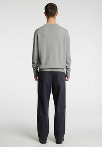 Meeste halli kootud kampsun ümmarguse kaelusega, pikkade varrukate ja soonikkoes äärega, kantud mereväe laia säärega pükste ja mustade saapadega.