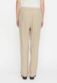 Beige Leinenhose mit elastischem Bund, geradem Bein und seitlichen Schlitzen am Saum. Weiche Textur, leichtes Material.