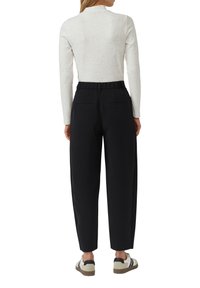 Biały top w cętki z długim rękawem, połączony z czarnymi, wysokim stanem spodniami z elastycznym paskiem w talii i dwoma tylnymi kieszeniami.