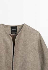 Světlohnědá strukturovaná bunda s otevřeným předním dílem, kulatým výstřihem, dlouhými rukávy a viditelnou černou značkou Massimo Dutti uvnitř límce.