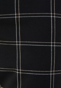 Černá látka se vzorem mřížky vyšitým bílou a zlatou nití. Texturovaný povrch s rovnoměrně rozestavenými vodorovnými a svislými liniemi.