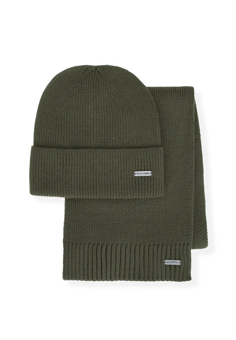 Zielony dziergany zestaw czapki i szalika, z prążkowaną teksturą, podwiniętym mankietem na czapce oraz małą metką z logo na obu elementach.