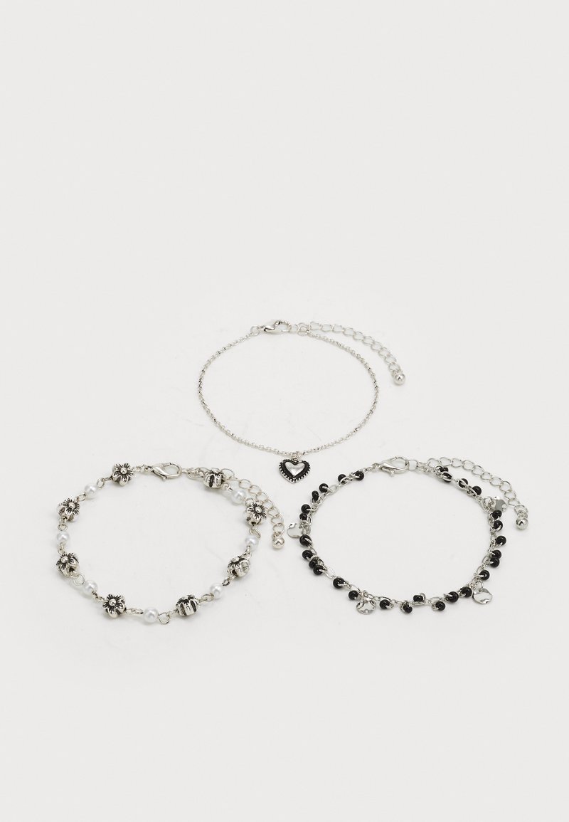 Drei Armbänder: eines mit Perlen und silbernen Akzenten, eines mit einem Herzanhänger und eines mit einem schwarzen Perlen-Design, die alle mit Kettengliedern verbunden sind.