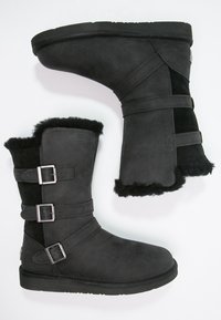 Bottines en daim noir avec doublure en fausse fourrure, dotées de deux sangles à boucle et d'une semelle plate. Le design comprend une finition texturée.