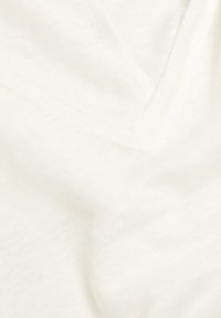 Tissu crème léger avec une texture douce, arborant un motif chiné subtil et un design en col en V.