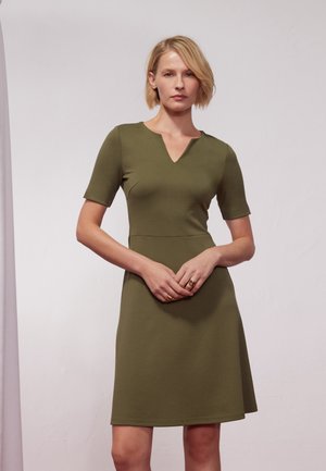 Olive green dress made of smooth, stretchy fabric with a V-neckline and short sleeves, featuring a fitted bodice and flared skirt.