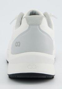 Weiße Sportschuhe mit einem strukturierten Mesh-Obermaterial und glatten grauen Akzenten, ausgestattet mit einer gepolsterten Ferse und einer schwarzen Gummisohle.