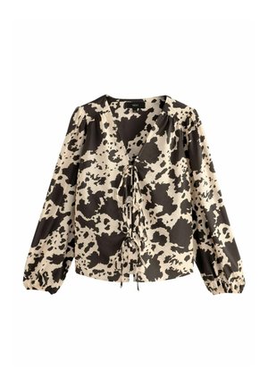 Long-sleeve blouse in cream and black cow print. Features a deep V-neck with a tied front and gathered sleeves with elastic cuffs.