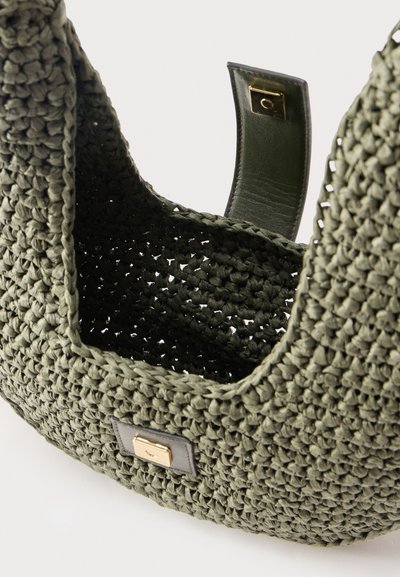 Close-up of a green woven handbag with a gold turn-lock clasp and an open top showing woven texture and interior.
