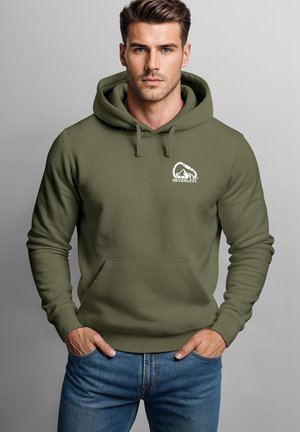 Mann trägt einen olivgrünen Kapuzenpullover mit Fronttaschen und einem weißen Berglogo mit der Aufschrift "NEVERLESS" auf der Brust, Hände in den Taschen.