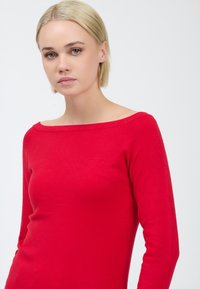 Rode trui met lange mouwen, een brede halslijn, een aansluitend ontwerp, een gladde textuur en naadloze schouders, met een effen kleur zonder patronen.