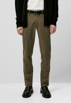 Khaki broek, van katoen, rechte pasvorm, ceintuurlussen, ritssluiting, gecombineerd met zwarte instappers en een zwarte cardigan. Smooth textuur.