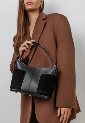 Black leather and suede handbag features a rectangular shape, smooth texture, and metal accent details. Logo visible on the side.