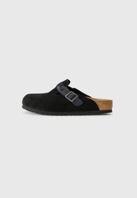 Black suede clog with a round toe, adjustable black buckle, and cork footbed. The outsole is textured for grip, with a slight color variation at the heel.