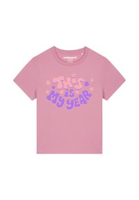 Roze katoenen t-shirt met een grafisch ontwerp en de tekst "DIT is MIJN JAAR" in lichtpaars en donkerblauw, verfraaid met kleine bloemetjes.