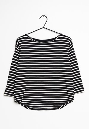 Černo-bíle pruhované tričko s dlouhým rukávem a kulatým výstřihem, volným střihem, zkoseným lemem a měkkou texturou látky.