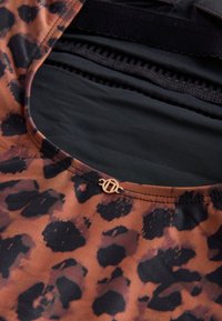 Leopard-print fabric in shades of brown and black with a smooth texture. Features a small gold-tone hardware accent at the neckline.