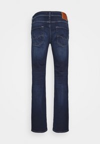Jeans en denim bleu foncé avec une coupe droite, comprenant deux poches arrière et une patch en cuir brun sur la taille.