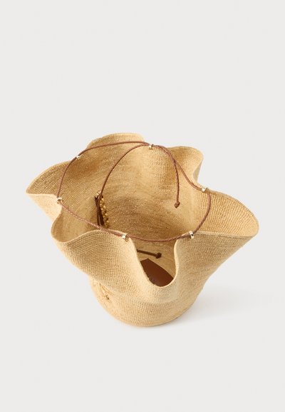 Ευρύχωρη τσάντα ώμου από πλεκτό ψάθινο με κυματιστά άκρα και λεπτό καφέ κορδόνι κλεισίματος που περνάει μέσα από μεταλλικά οπλισμένα τρύπες.