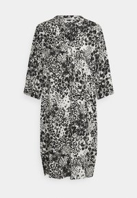 Robe chemise à imprimé léopard noir et blanc avec un col, des manches longues et deux poches avant, fabriquée à partir d'un tissu léger et fluide.