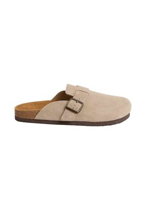 Beige ruskindsklog med justerbar spænde. Har en korkindlægssål og en brun gummisål. Rundet tå og åben bagdesign.