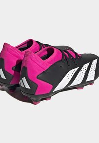 Schwarze und pinke Fußballschuhe mit strukturierten Oberflächen, weißen Akzenten, Schnürdesign und geformten Kunststoffstollen.