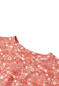 Koralfarvet stof med tæt hvidt og lyserødt blomsterprint, der viser små blomster og blade, vist i et nærbillede af et halsudskæringsområde.