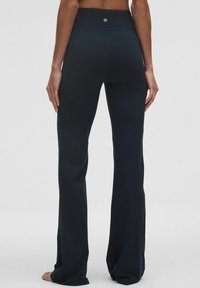 Sorte, højtaljede flared leggings lavet af glat stof, med et logo bagpå og en ren, skræddersyet pasform.