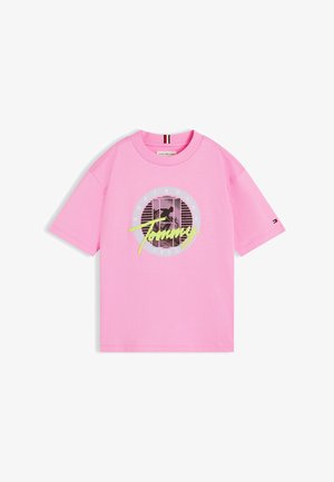 Pink T-shirt med korte ærmer med sort-hvid cirkulær grafik, neongul "Tommy" tekst og lille flaglogo på ærmet.