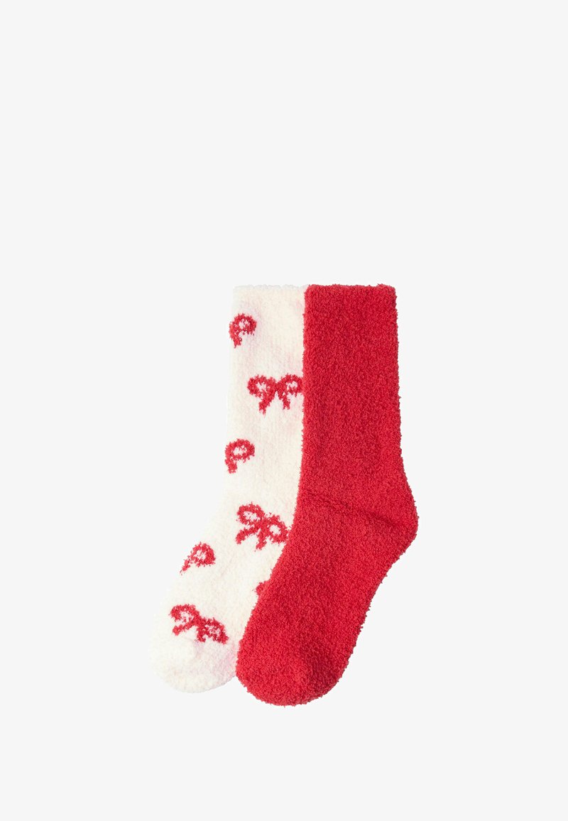 Røde og hvide fluffy sokker; en med ensfarvet rød finish, den anden har en hvid baggrund med røde sløjfemønstre. Blød tekstur.