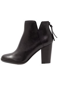 Botín de cuero negro hasta el tobillo con punta redonda, diseño en forma de V y un tacón alto en bloque. Incluye una pequeña tira decorativa en la parte posterior.